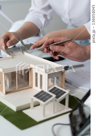 Two people are working on a model of a house Two people are working on a model of a house 136058045