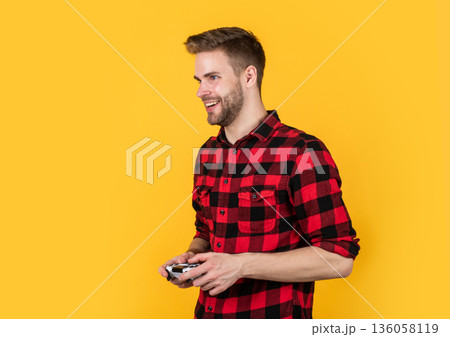 living in digital world. male hobby and free time. gamer in checkered shirt. happy bearded guy use game console. unshaven handsome man with joystick. play computer video and online game 136058119