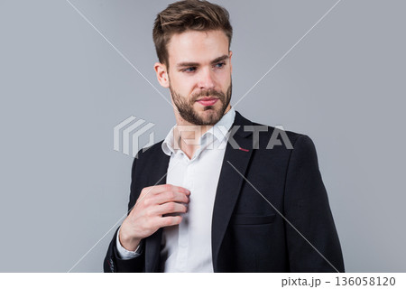 Feeling flirty. Young manager in his office. portrait of a businessman on grey background. confident businessman portrait. Portrait of a handsome CEO. Businessman in suit. Young handsome man Feeling flirty. Young manager in his office. portrait of a businessman on grey background. confident businessman portrait. Portrait of a handsome CEO. Businessman in suit. Young handsome man 136058120
