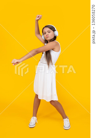teen girl listen music in headphones and danc on yellow background teen girl listen music in headphones and danc on yellow background 136058270