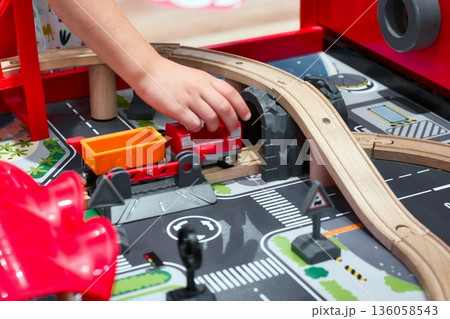 Close-up of a child's arm and hand playing with a toy train set Close-up of a child's arm and hand playing with a toy train set 136058543