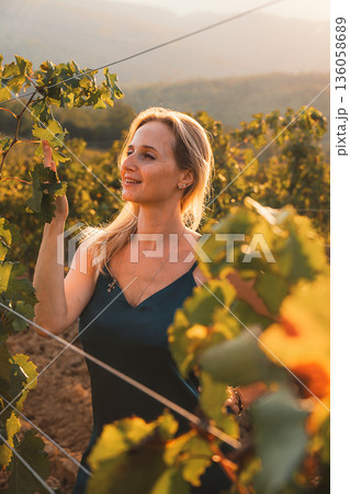 Woman Enjoying Nature in a Sunlit Vineyard 136058689