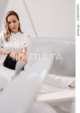 Portrait of doctor performing mesotherapy microneedling on woman face, providing skin rejuvenation and professional cosmetic care in aesthetic clinic. Concept of facial anti-aging, skincare treatment. 136059267