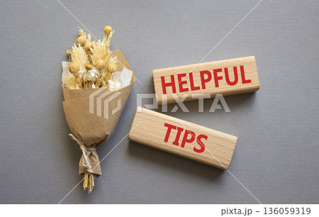 Helpful tips symbol. Wooden blocks with words Helpful tips. Beautiful grey background with bouquet of flowers. Business and Helpful tips concept. Copy space. 136059319
