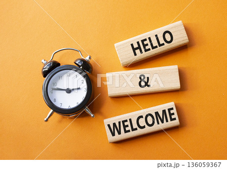 Hello and Welcome symbol. Concept words Hello and Welcome on wooden blocks. Beautiful orange background with alarm clock. Business and Hello and Welcome concept. Copy space. 136059367