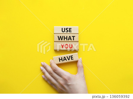 Use what you Have symbol. Concept words Use what you Have on wooden blocks. Beautiful bright yellow background. Businessman hand. Business and Use what you Have concept. Copy space. 136059392