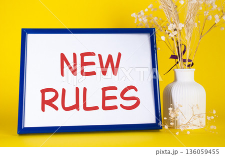 New rules symbol. Concept words New rules on beautiful wooden picture frame. Beautiful yellow background with flower vase. Business and New rules concept. Copy space. New rules symbol. Concept words New rules on beautiful wooden picture frame. Beautiful yellow background with flower vase. Business and New rules concept. Copy space. 136059455