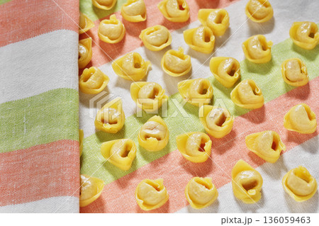 Uncooked tortellini pasta on colored cloth 136059463