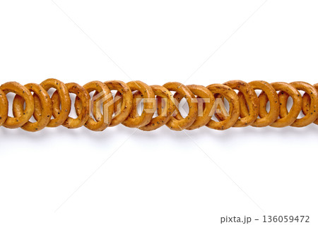 Salted pretzels with poppy seeds lined up in a row isolated on white background. 136059472