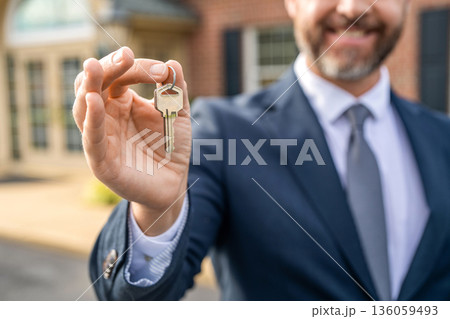 Realtor in suit hold key outdoor. Real estate agent showing house for sale. Property insurance. Real estate market. Selective focus. Broker man. House insurance. Realtor offering new home 136059493