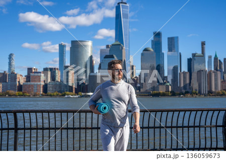 Sport man ready for workout. Healthy lifestyle. Fitness and sport. Yoga mat for training. Sportsman in New York. Man in sportswear with fitness mat in Manhattan. Yoga coach. Athletic workout Sport man ready for workout. Healthy lifestyle. Fitness and sport. Yoga mat for training. Sportsman in New York. Man in sportswear with fitness mat in Manhattan. Yoga coach. Athletic workout 136059673