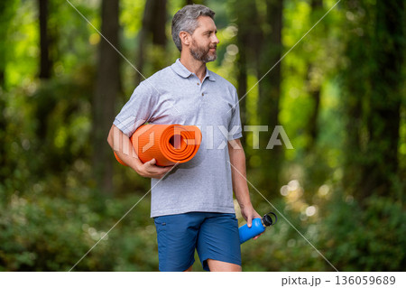 Man in sportswear with fitness mat and water. Fit and hydrate your body. Yoga coach. Sport man at workout. Healthy lifestyle. Fitness and sport. Yoga mat for training. Sportsman keep water balance Man in sportswear with fitness mat and water. Fit and hydrate your body. Yoga coach. Sport man at workout. Healthy lifestyle. Fitness and sport. Yoga mat for training. Sportsman keep water balance 136059689