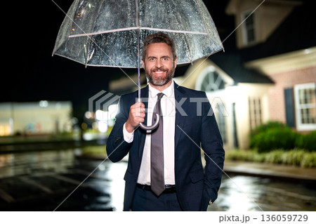 Businessman with umbrella in rain night. Business patience. Businessman waiting at rain. Businessman at night street. Man in suit waiting outdoor. Man waiting in rainy weather Businessman with umbrella in rain night. Business patience. Businessman waiting at rain. Businessman at night street. Man in suit waiting outdoor. Man waiting in rainy weather 136059729