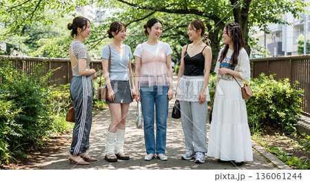 新緑の公園で談笑する若い女性グループ カジュアルな私服ファッションと友情 136061244