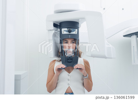 Woman undertaking panoramic dental x-ray scan procedure Woman undertaking panoramic dental x-ray scan procedure 136061599