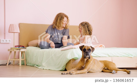 Mother and daughter reading story with boxer dog Mother and daughter reading story with boxer dog 136061657
