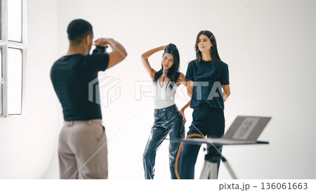 Photographer taking photos of two fashion models in studio 136061663