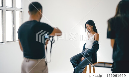 Photographer taking pictures of model posing in studio Photographer taking pictures of model posing in studio 136061669