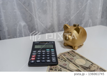 お金の計算をする豚の貯金箱と電卓 136061745