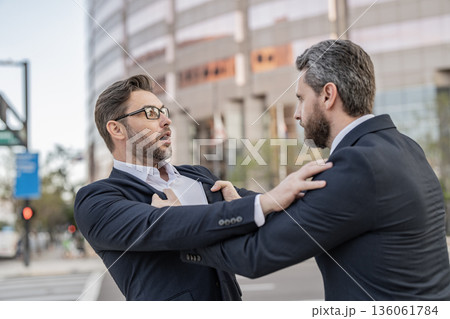 Two businessmen conflicting at fight outdoor. Businessmen having conflict in business. Conflict between boss and employee. Fight aggression. Angry businessmen threatening. Business conflict 136061784