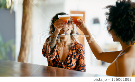 Women toasting tropical cocktails at a bar Women toasting tropical cocktails at a bar 136061892