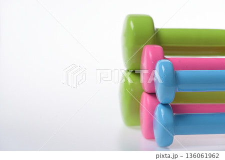 Dumbbells made of blue, pink and green plastic on white Dumbbells made of blue, pink and green plastic on white 136061962