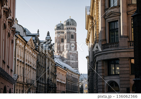 Historic Munich Old Town Street With Cathedral Of Our Dear Lady: Narrow Urban Alley Framing Iconic Twin Domed Church Towers And Traditional Bavarian Architecture Historic Munich Old Town Street With Cathedral Of Our Dear Lady: Narrow Urban Alley Framing Iconic Twin Domed Church Towers And Traditional Bavarian Architecture 136062366