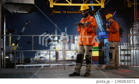 Industrial engineer inspect offshore drilling rig systems using tablet to monitor emissions while extracting natural gas and petroleum. Ensuring efficient oil production for the industry. Industrial engineer inspect offshore drilling rig systems using tablet to monitor emissions while extracting natural gas and petroleum. Ensuring efficient oil production for the industry. 136063071