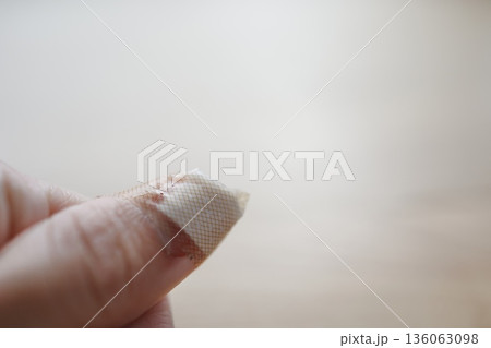 親指の怪我に絆創膏を貼った手元のクローズアップ。 136063098
