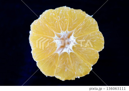 黒背景に配置した外皮を剥いたみかん断面のクローズアップ。 136063111