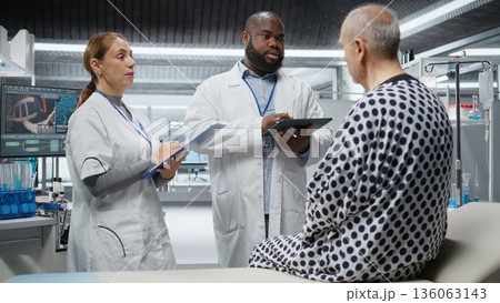 Team of scientists conducting clinical research and testing on a patient to evaluate new drug effects, monitoring vitals. People study reactions, progress in healthcare development. Camera A. Team of scientists conducting clinical research and testing on a patient to evaluate new drug effects, monitoring vitals. People study reactions, progress in healthcare development. Camera A. 136063143