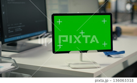 Green screen tablet in empty startup office with artificial intelligence program running on monitors. Mockup device in AI industry startup workspace leveraging deep learning tech enhancing automation 136063318