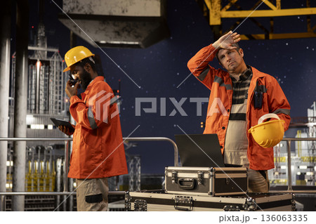 Agitated oil rig inspection officer evaluates fuel production systems and sweating, working in tension to ensure petroleum compliance and natural fuel extraction. Concerned engineer. Agitated oil rig inspection officer evaluates fuel production systems and sweating, working in tension to ensure petroleum compliance and natural fuel extraction. Concerned engineer. 136063335
