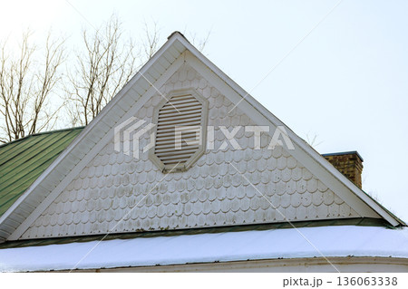 Roof with shingles, ventilation peaks over snow covered ground leafless trees. 136063338