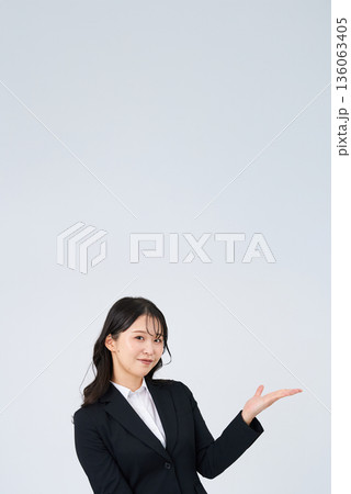 案内のポーズをするスーツ姿の女性 案内のポーズをするスーツ姿の女性 136063405