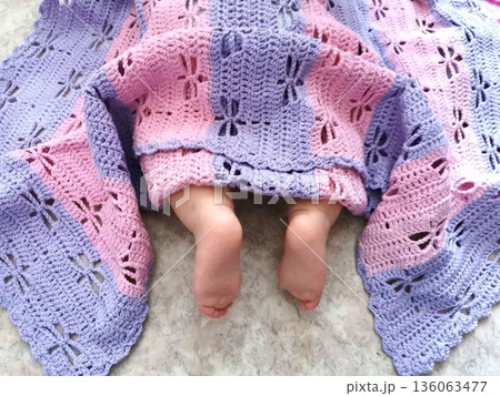 Delicate feet of a newborn under a soft handmade knitted blanket Delicate feet of a newborn under a soft handmade knitted blanket 136063477