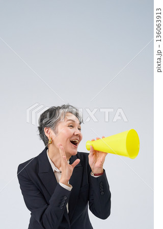 応援のポーズをするスーツ姿のシニア女性 136063913