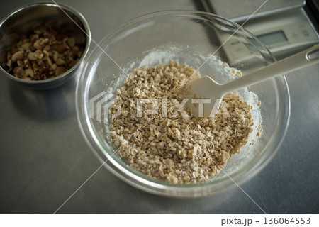 グラノーラを作るためにオートミールと小麦粉と砂糖を混ぜているところ グラノーラを作るためにオートミールと小麦粉と砂糖を混ぜているところ 136064553