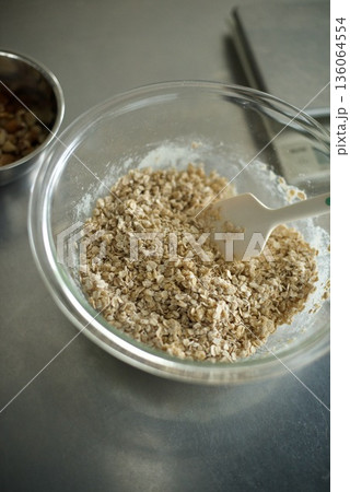 グラノーラを作るためにオートミールと小麦粉と砂糖を混ぜているところ グラノーラを作るためにオートミールと小麦粉と砂糖を混ぜているところ 136064554