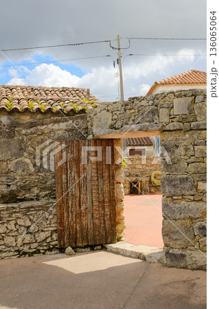 Old stone gateway with wooden door opening to rustic courtyard traditional village architecture Fatima Portugal no people. High quality photo 136065064
