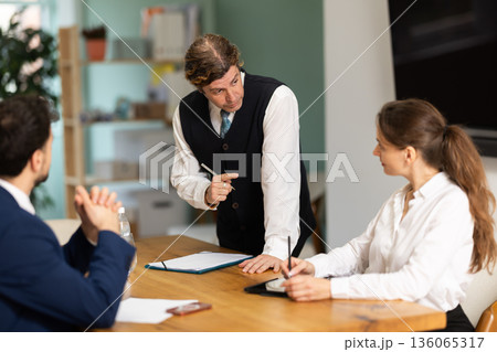 Working atmosphere, business colleagues gathering at table, and man participant stands up 136065317