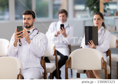 Medical students or doctors using mobile phones to scan QR-code during interactive lesson Medical students or doctors using mobile phones to scan QR-code during interactive lesson 136065323