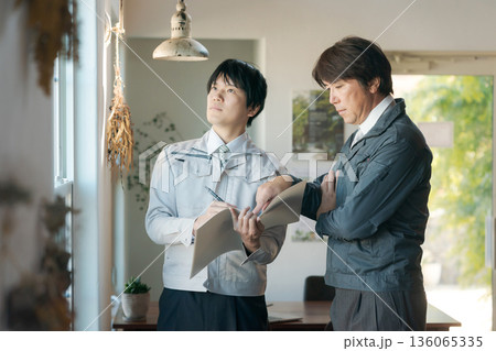 窓の前で打ち合わせする作業服の男性 136065335