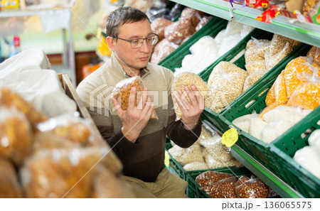Male shopper selects various nuts in the produce section of supermarket Male shopper selects various nuts in the produce section of supermarket 136065575