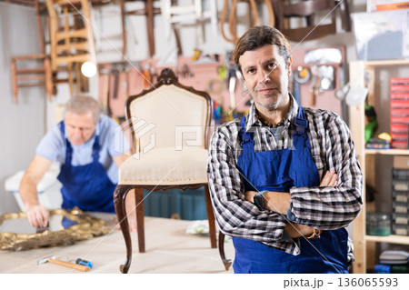 Confident male carpenter showing around local furniture workshop 136065593