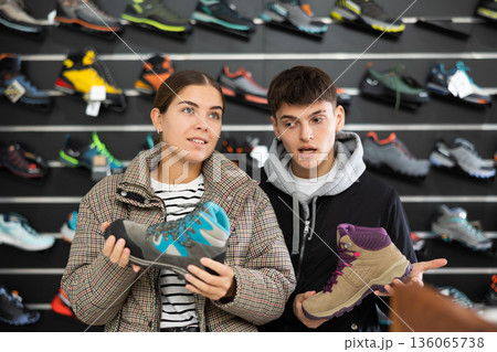 Couple examine view several item of winter comfortable trecking shoes Couple examine view several item of winter comfortable trecking shoes 136065738