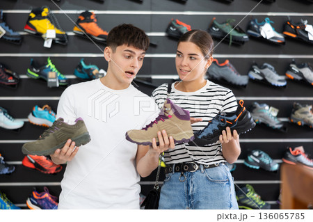 Guy with girlfriend, view specialized shoes in store, near showcase with summer trecking cross-shoes Guy with girlfriend, view specialized shoes in store, near showcase with summer trecking cross-shoes 136065785