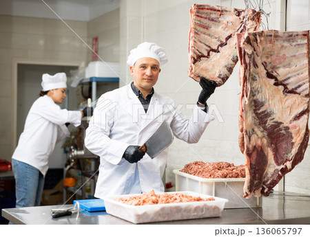 Butcher checking raw beef ribs at meat processing table 136065797