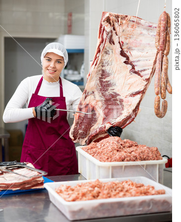 Young woman butcher holding beef ribs 136065802