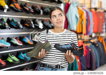 Girl examine compare item of autumn comfortable tracking shoes Girl examine compare item of autumn comfortable tracking shoes 136065826